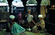 8. Volkmar Wentzel - India - 1947. Seduti su un balcone affacciato sulla valle del Kashmir alcuni tessitori con il turbante fumano intensamente una pipa ad acqua